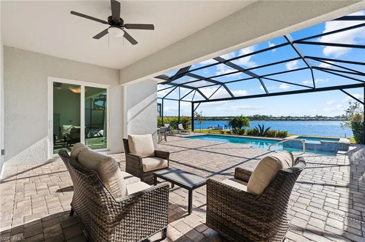 View of patio featuring an outdoor hangout area, a lanai, a pool with hot tub, ceiling fan, and a water view