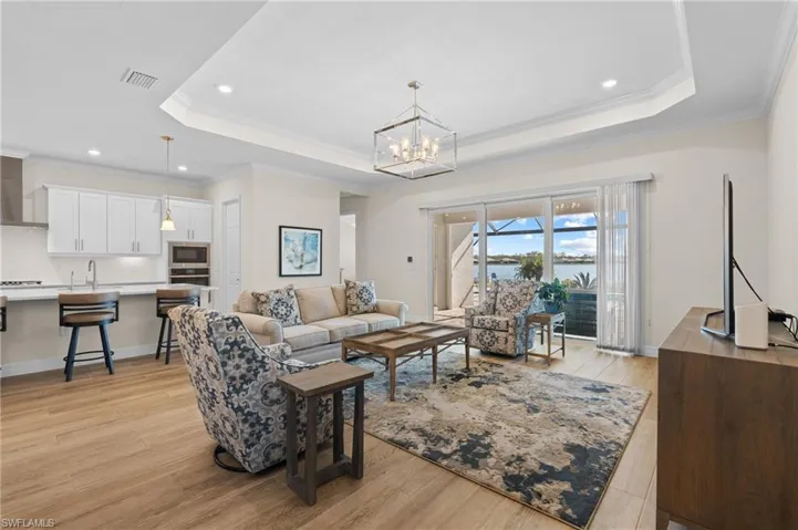 Living room with light hardwood / wood-style floors, a tray ceiling, and crown molding