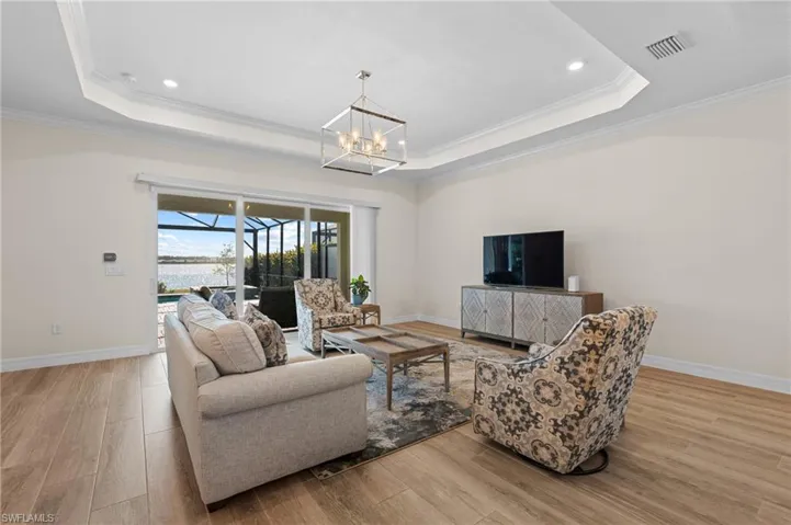 Living room featuring a tray ceiling, crown molding, and light hardwood / wood-style floors