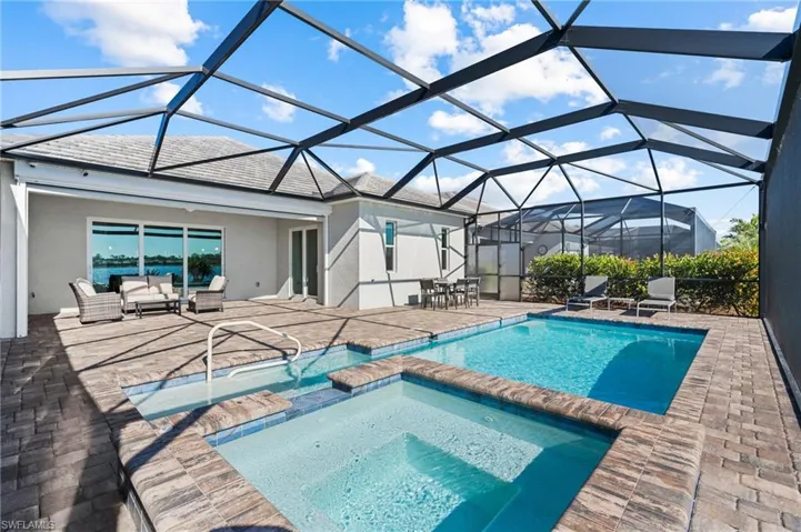 View of swimming pool featuring outdoor lounge area, glass enclosure, a patio area, and an in ground hot tub