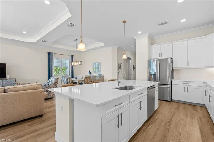 Kitchen with sink, decorative light fixtures, light hardwood / wood-style floors, white cabinetry, and stainless steel appliances