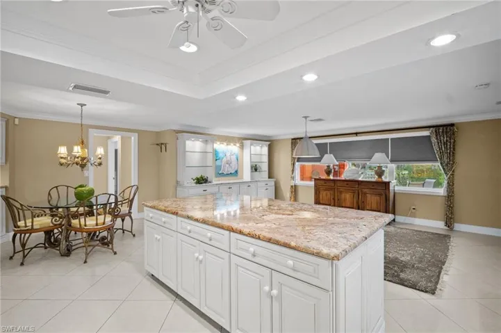 Kitchen featuring visible vents, light tile patterned flooring, crown molding, a raised ceiling, and a center island