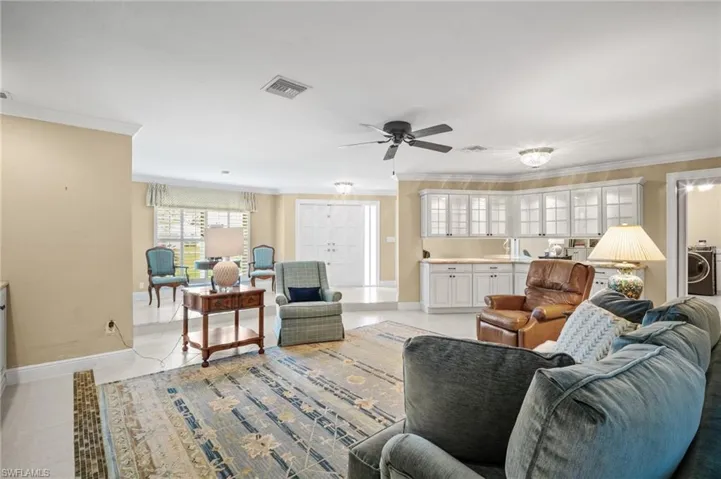 Living room featuring visible vents, baseboards, washer / dryer, light tile patterned flooring, and crown molding