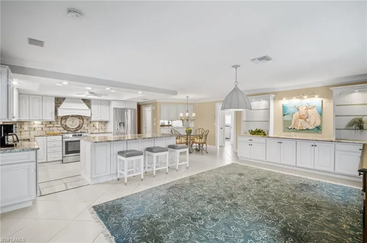Kitchen with custom exhaust hood, visible vents, stainless steel appliances, and light tile patterned floors