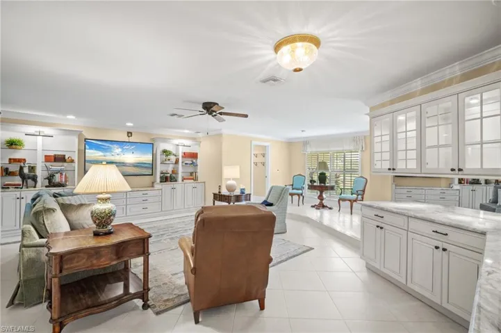 Living area featuring light tile patterned floors, recessed lighting, visible vents, and ornamental molding