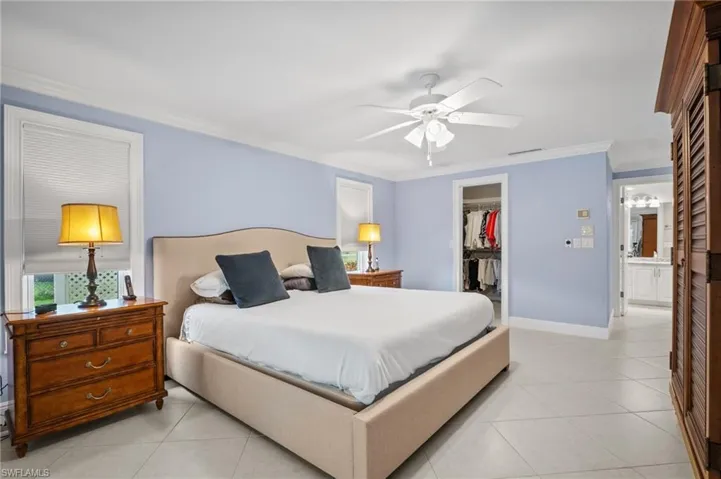 Bedroom with a spacious closet, light tile patterned flooring, a closet, and ornamental molding