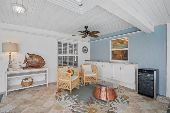 Living area featuring a ceiling fan, wooden ceiling, beverage cooler, and beam ceiling