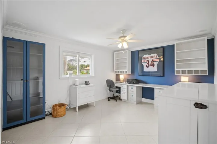 Office space featuring light tile patterned flooring, baseboards, crown molding, and ceiling fan