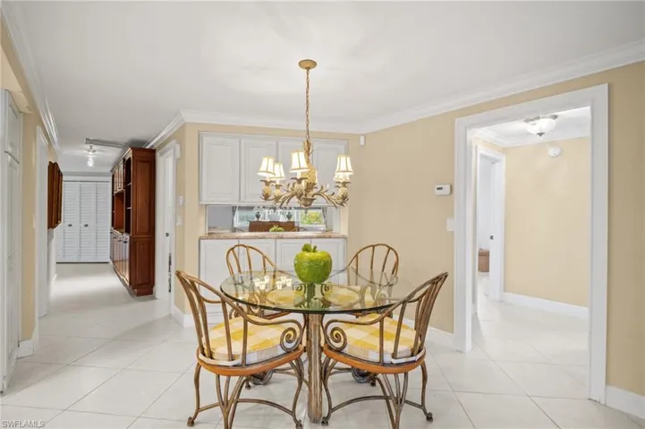 Dining area with a chandelier, crown molding, baseboards, and light tile patterned flooring