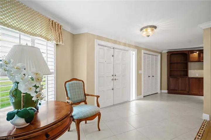 Foyer featuring light tile patterned floors, baseboards, and ornamental molding