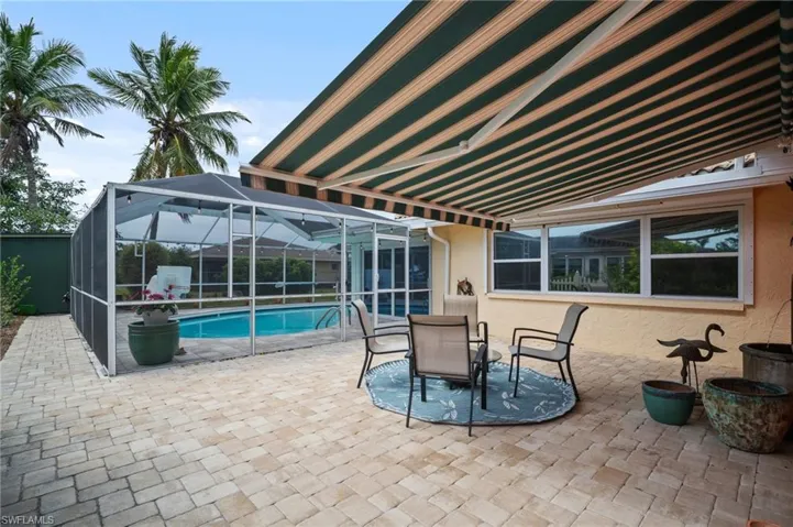 View of patio / terrace with glass enclosure, outdoor dining area, and an outdoor pool