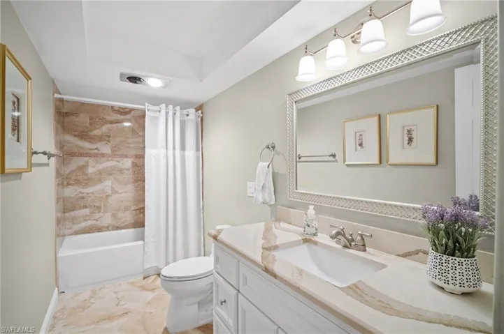 Full bathroom featuring vanity, toilet, shower / bath combo, and marble finish floor