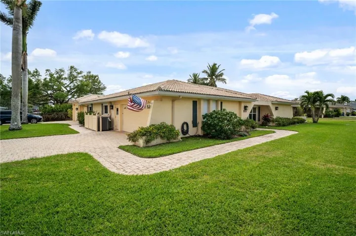 Ranch-style house with a tile roof, a front yard, stucco siding, decorative driveway, and an attached garage