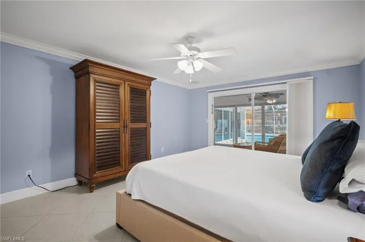 Bedroom featuring a ceiling fan, crown molding, light tile patterned floors, baseboards, and access to exterior