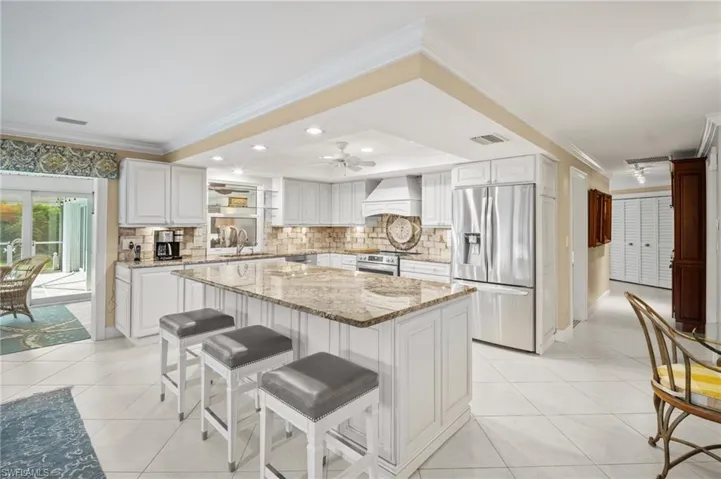 Kitchen featuring light tile patterned floors, custom exhaust hood, appliances with stainless steel finishes, and a sink