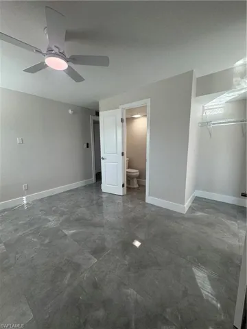 Unfurnished bedroom with ceiling fan, connected bathroom, and a closet