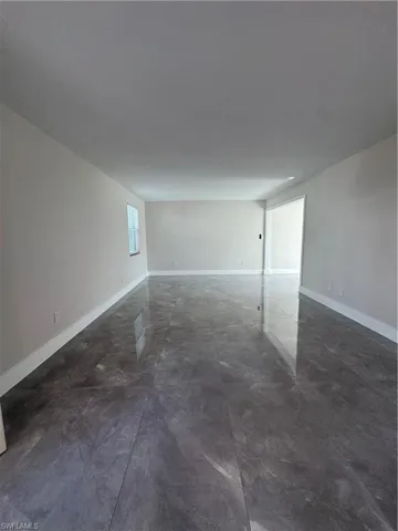 Spare room featuring baseboards and concrete flooring