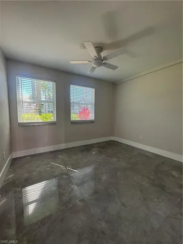 Unfurnished room with concrete floors, ceiling fan, and healthy amount of natural light