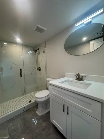 Bathroom with vanity and a marble finish shower
