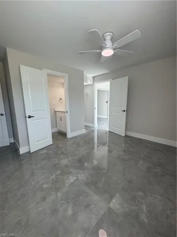Unfurnished bedroom featuring ceiling fan and ensuite bath
