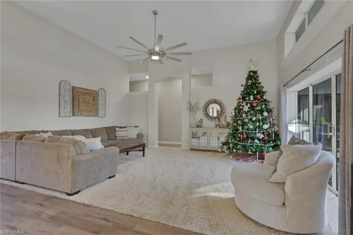 Living area featuring a high ceiling, a ceiling fan, arched walkways, and wood finished floors