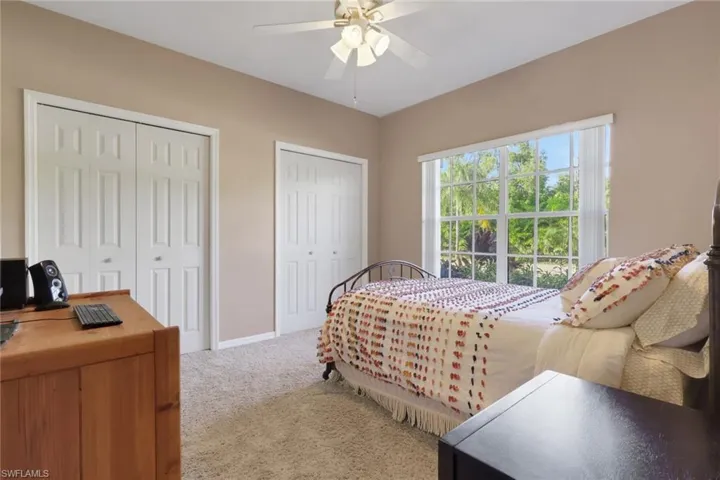Bedroom with multiple closets, light carpet, and ceiling fan