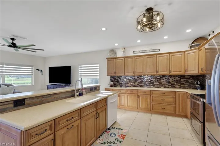 Kitchen with stainless steel appliances, light tile patterned floors, backsplash, ceiling fan, and recessed lighting