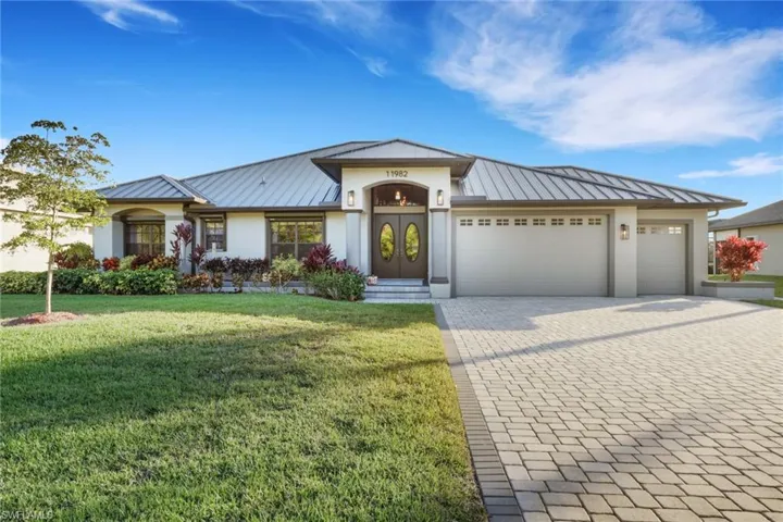 View of front facade with a standing seam roof, a metal roof, decorative driveway, and a front lawn