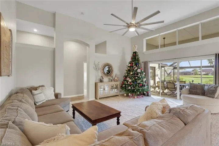 Carpeted living room featuring a ceiling fan and a towering ceiling