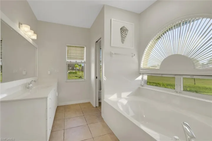 Full bath with vanity, a bath, and light tile patterned floors