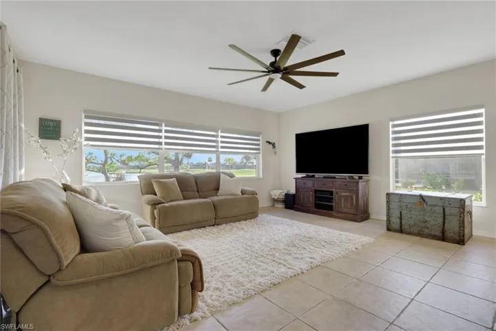 Living area featuring plenty of natural light, light tile patterned floors, and a ceiling fan