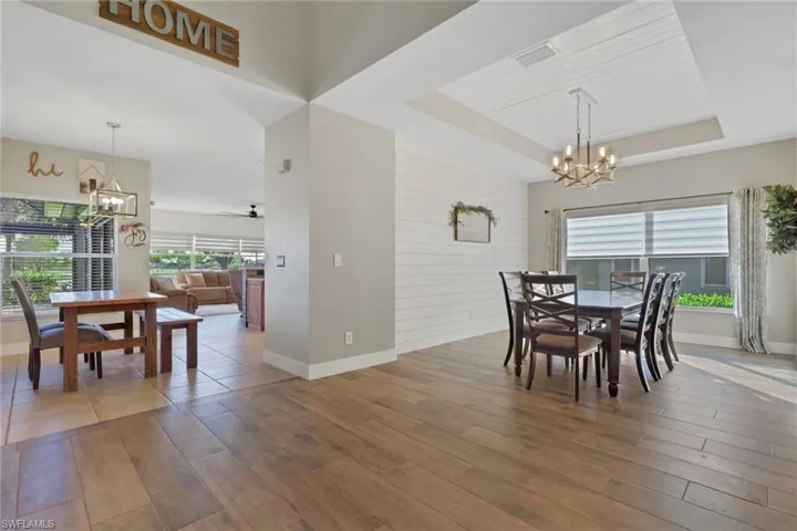 Dining area featuring a chandelier, light wood-type flooring, a raised ceiling, and ceiling fan
