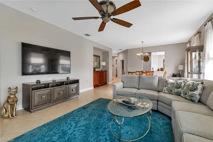 Living room featuring light tile patterned floors and ceiling fan with notable chandelier