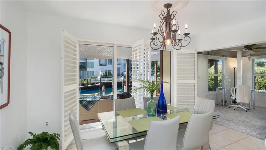 Carpeted dining room with ceiling fan with notable chandelier