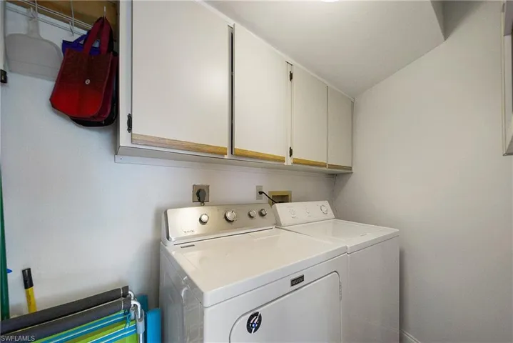 Clothes washing area featuring independent washer and dryer and cabinets