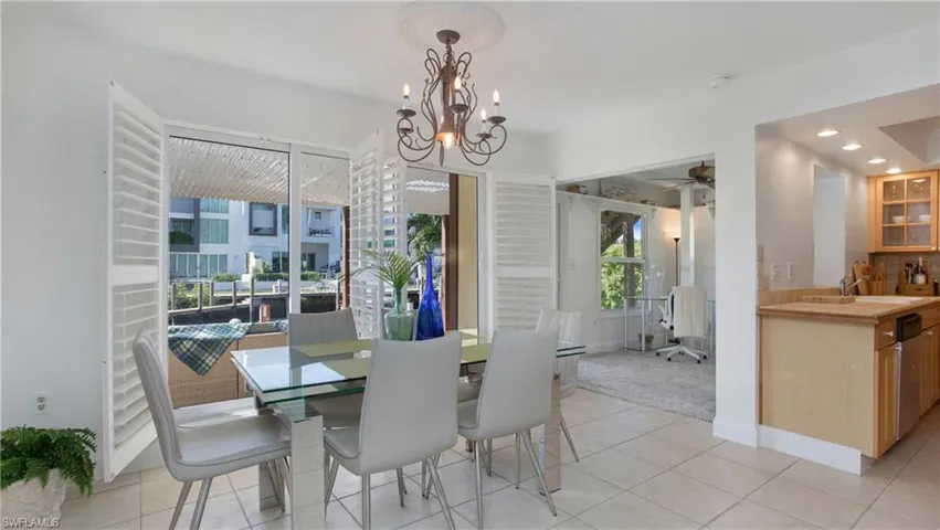 Dining space featuring sink, ceiling fan with notable chandelier, and light tile patterned floors