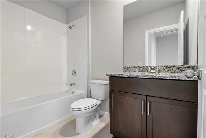 Full bathroom featuring tiled shower / bath, vanity, toilet, and tile floors