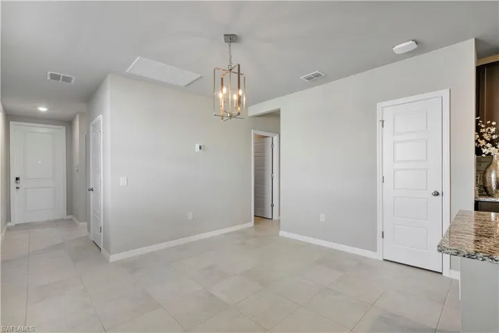 Spare room featuring an inviting chandelier and light tile flooring