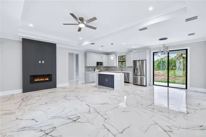 Kitchen with open floor plan, light countertops, stainless steel appliances, a ceiling fan, and a center island