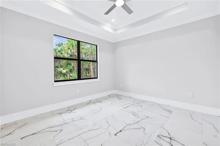 Spare room featuring marble finish flooring, ceiling fan, a raised ceiling, recessed lighting, and ornamental molding