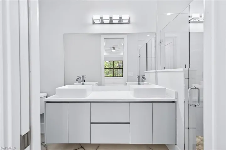 Full bathroom featuring double vanity and a shower stall