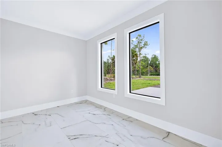 Empty room featuring marble look tile flooring and crown molding