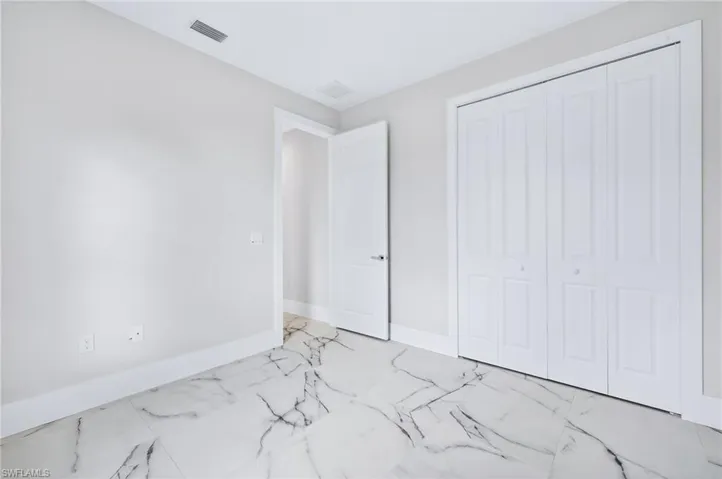 Unfurnished bedroom featuring light marble finish floors and a closet