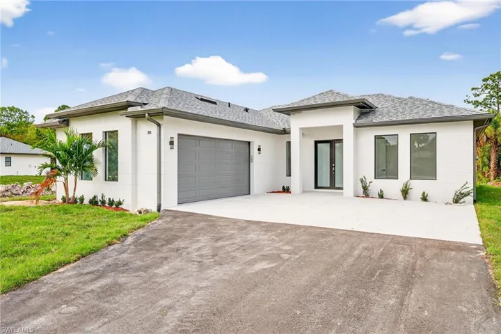 Prairie-style home with a garage, driveway, french doors, stucco siding, and roof with shingles