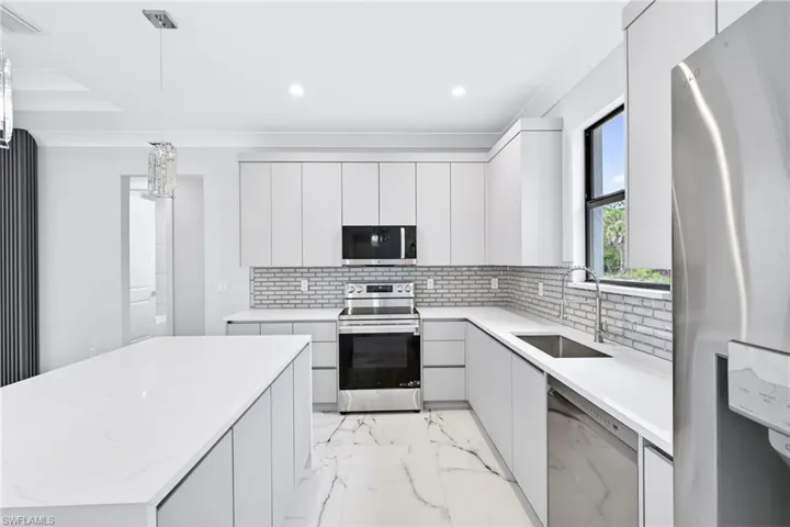 Kitchen featuring stainless steel appliances, pendant lighting, backsplash, and modern cabinets