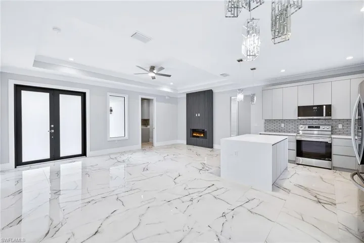 Kitchen featuring open floor plan, stainless steel appliances, pendant lighting, ceiling fan, and a center island