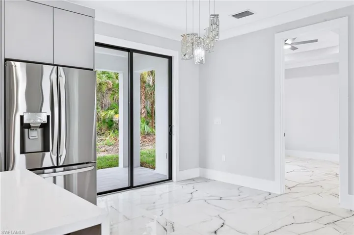 Unfurnished dining area featuring light marble finish flooring, a chandelier, and crown molding