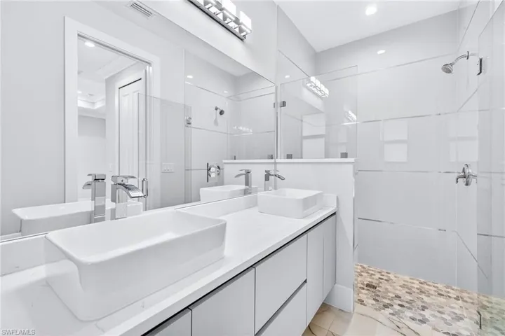 Full bath with a stall shower, double vanity, and recessed lighting