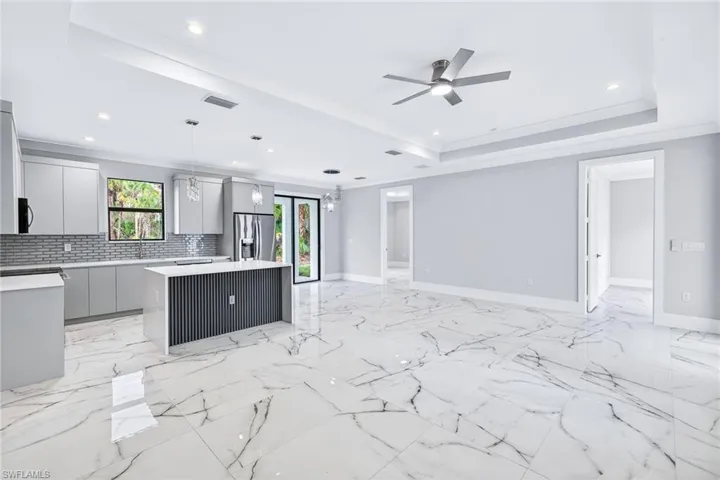 Kitchen featuring open floor plan, a ceiling fan, a center island, modern cabinets, and tasteful backsplash