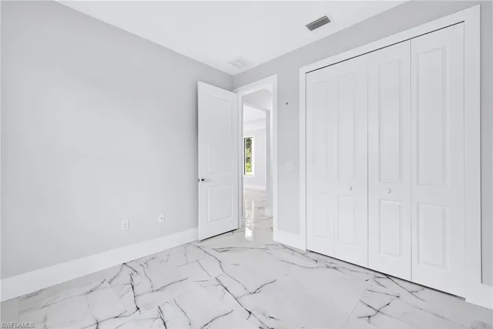 Unfurnished bedroom with light marble finish floors and a closet